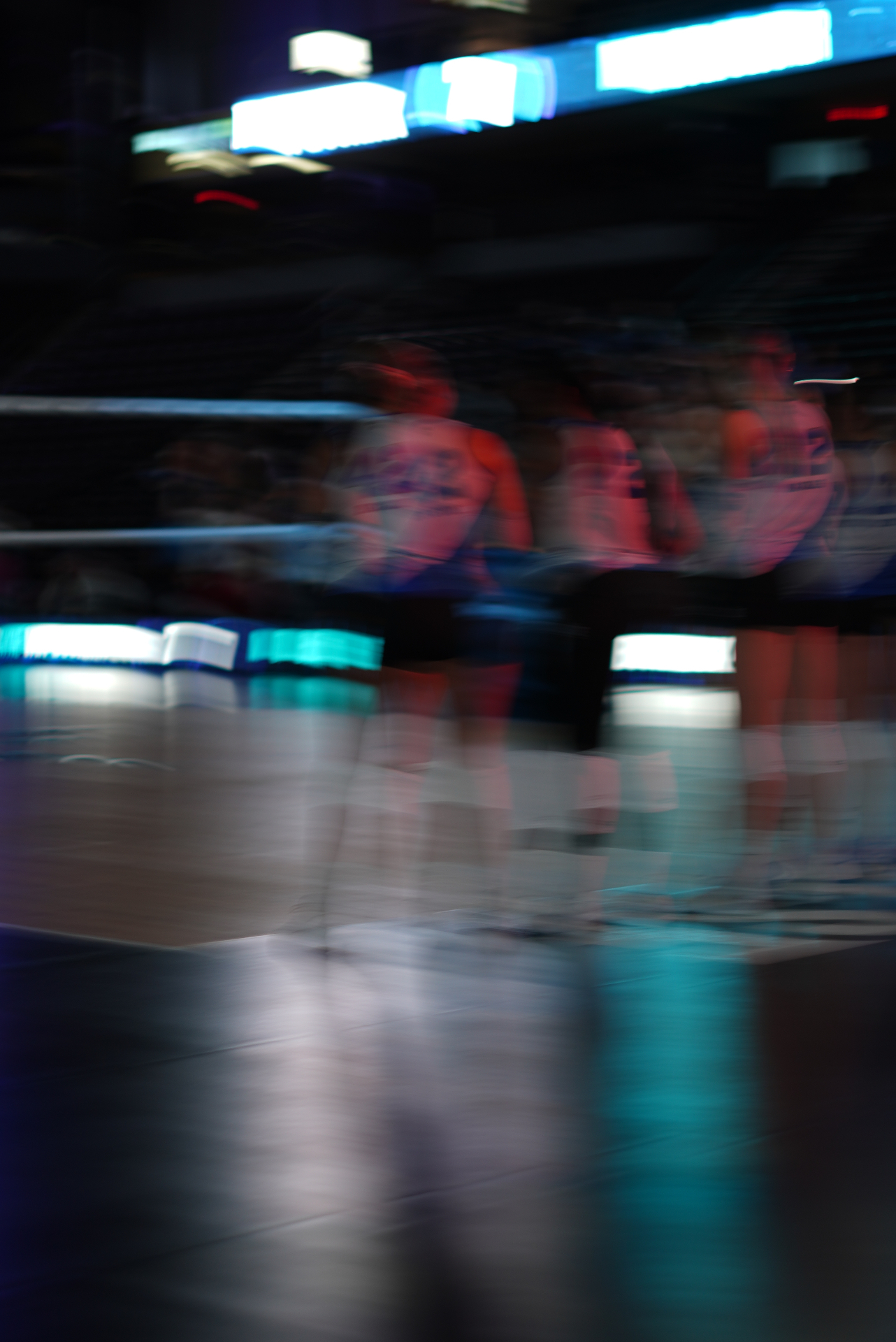 Motion-blurred volleyball players entering the court